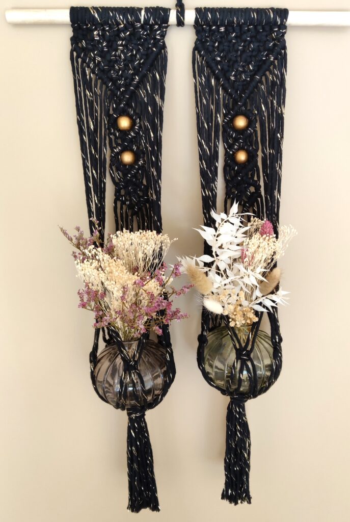 Suspension murale en macramé noir avec des perles en bois dorées, ajoutant une touche bohème et chic à la décoration intérieure
